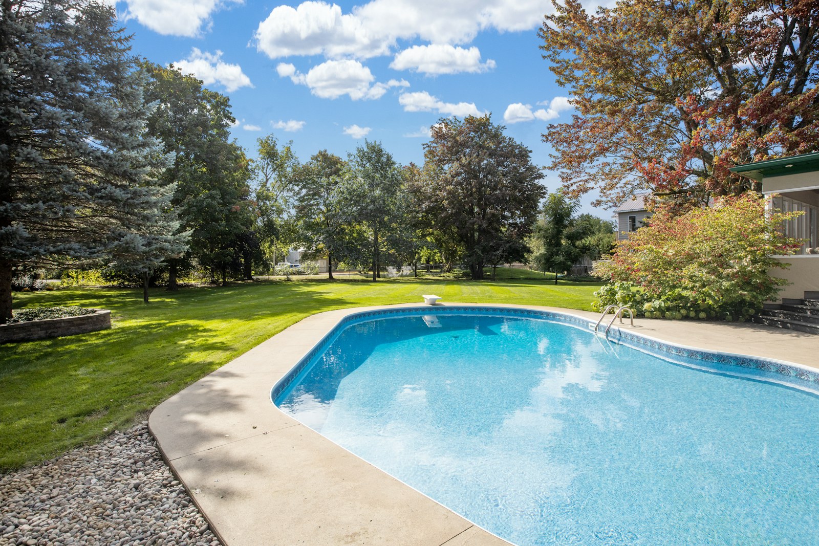 Real residential swimming pool bordered by trees beginning to change color
